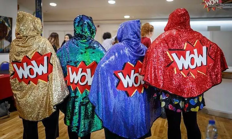 Four sparkly WoW capes being modelled here by four volunteers.